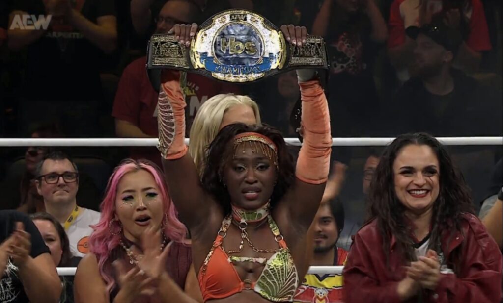 Queen Aminata raises the TBS Championship as fellow wrestlers celebrate her title win on AEW Dynamite Fright Night, October 28, 2026.